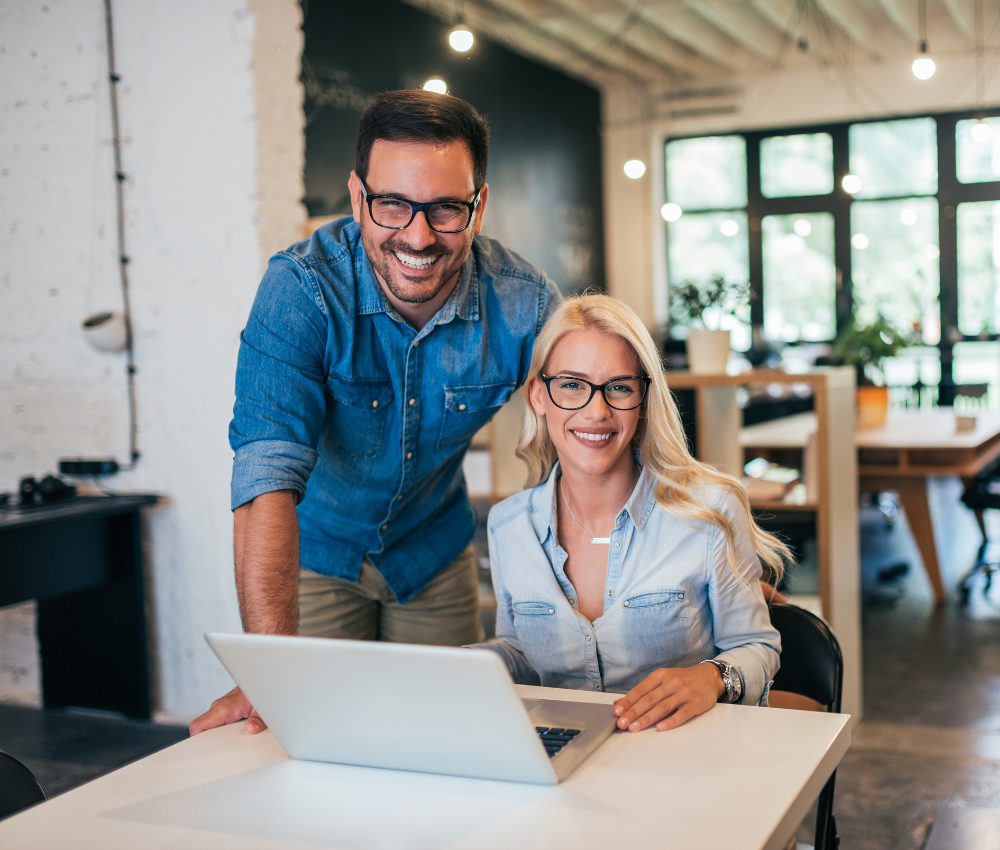 Man and woman smiling and typing on a laptop