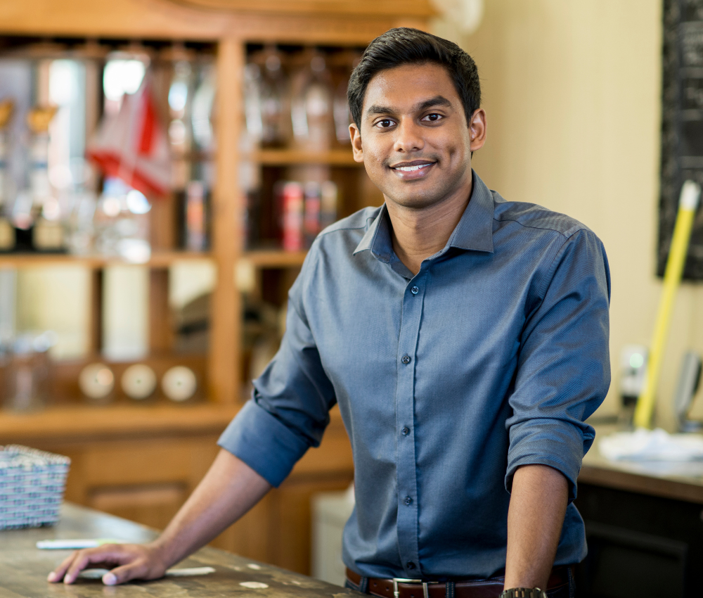 Business owner wearing a grey button up shirt smiling