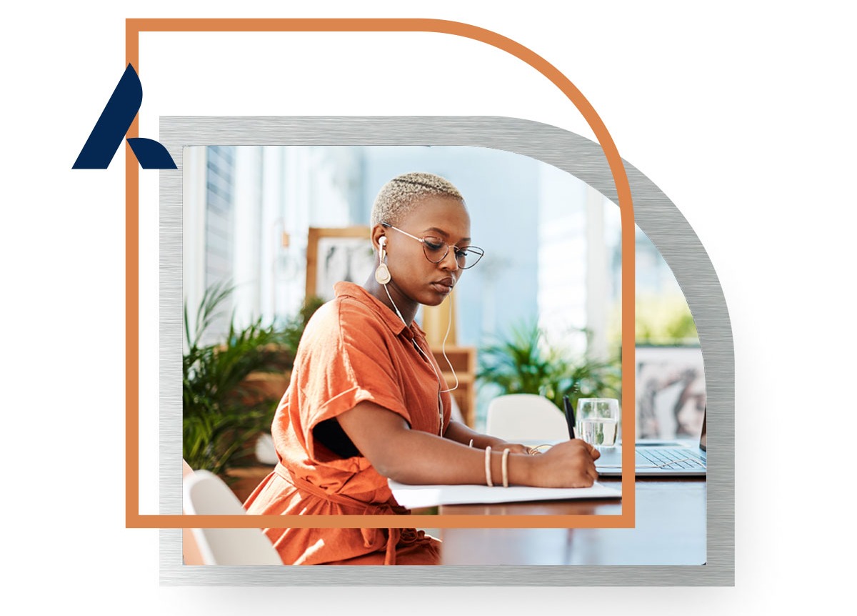 Business woman in orange dress working at her desk with airpods in