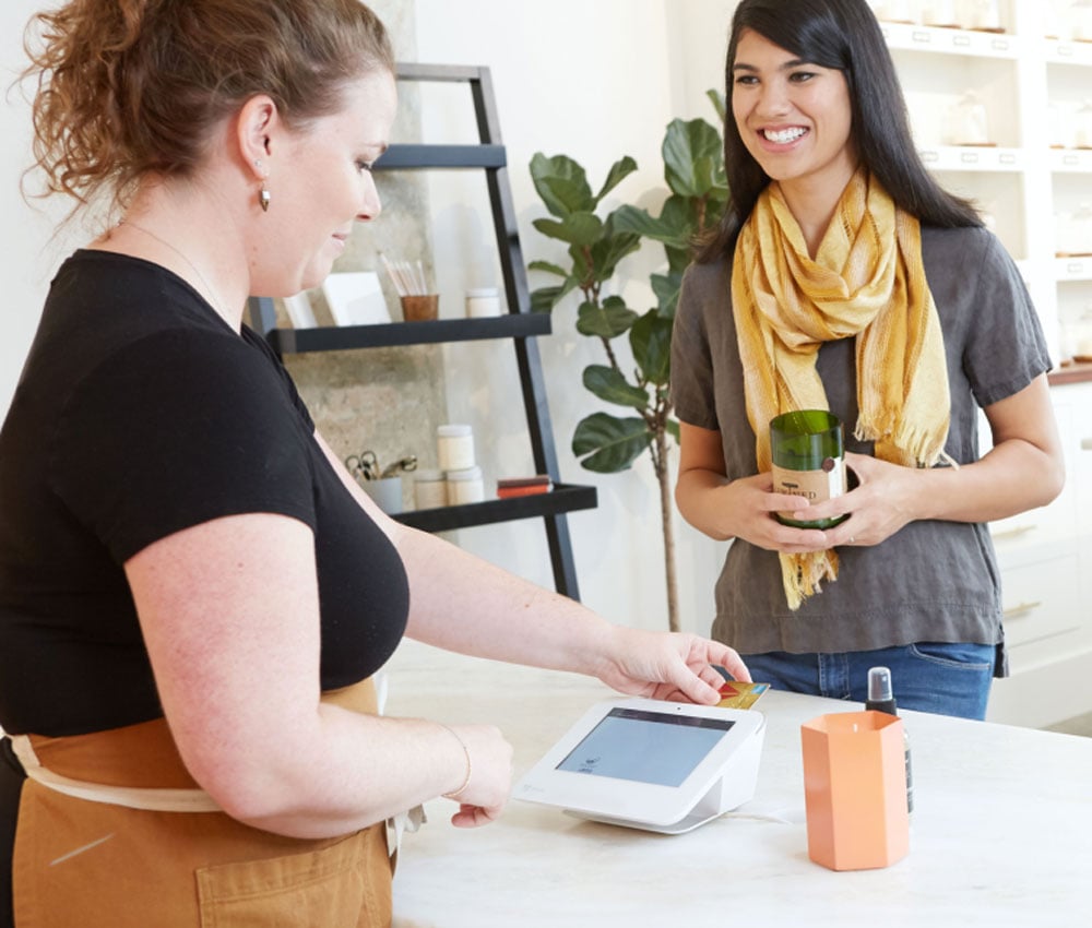 Business worker using tap to pay for her customer who is purchasing a candle.