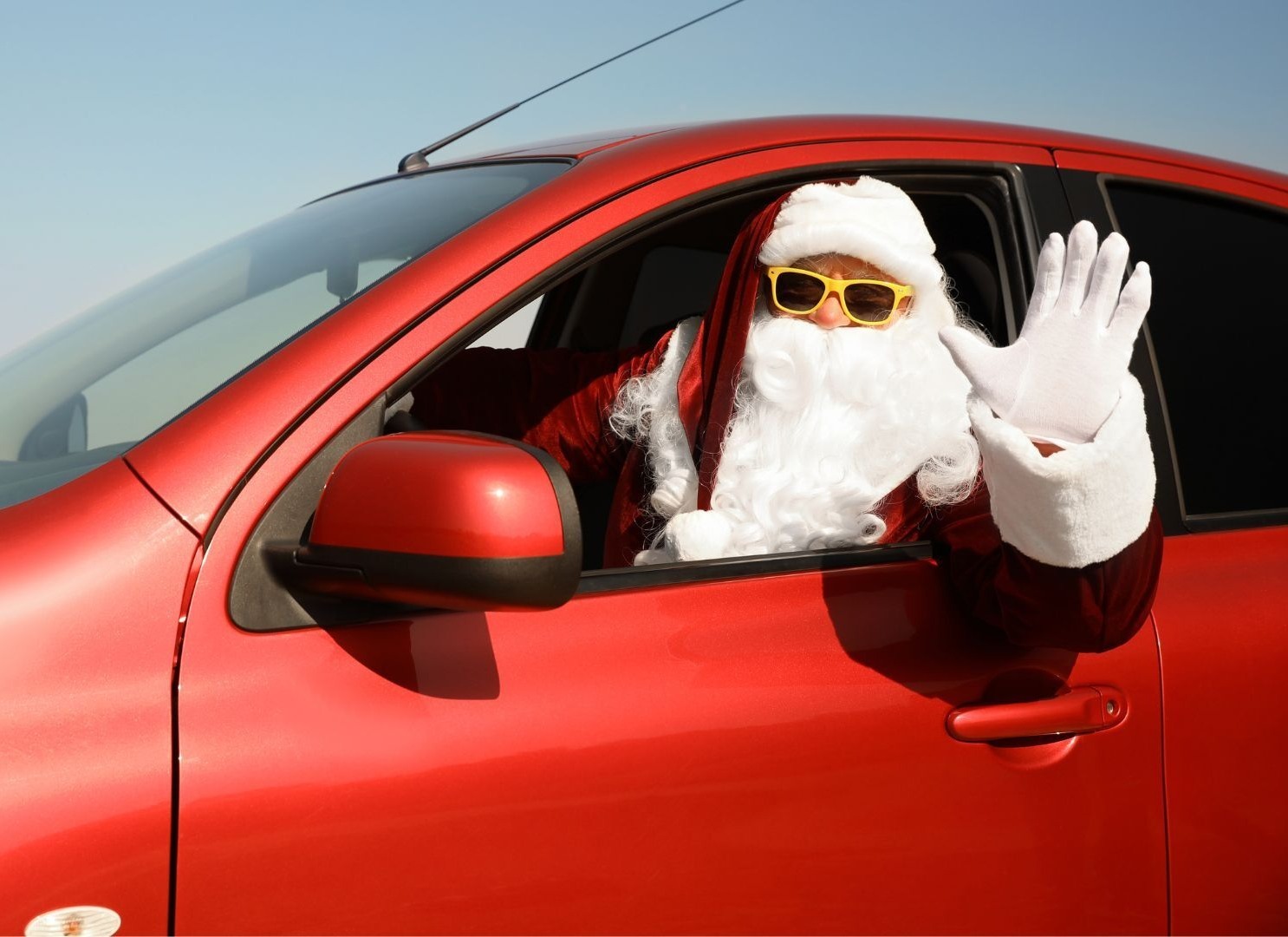 Santa driving a red car waving out the window
