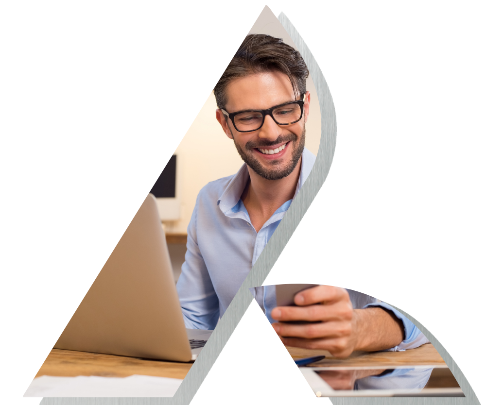Man wearing glasses with a laptop holding a phone and smiling