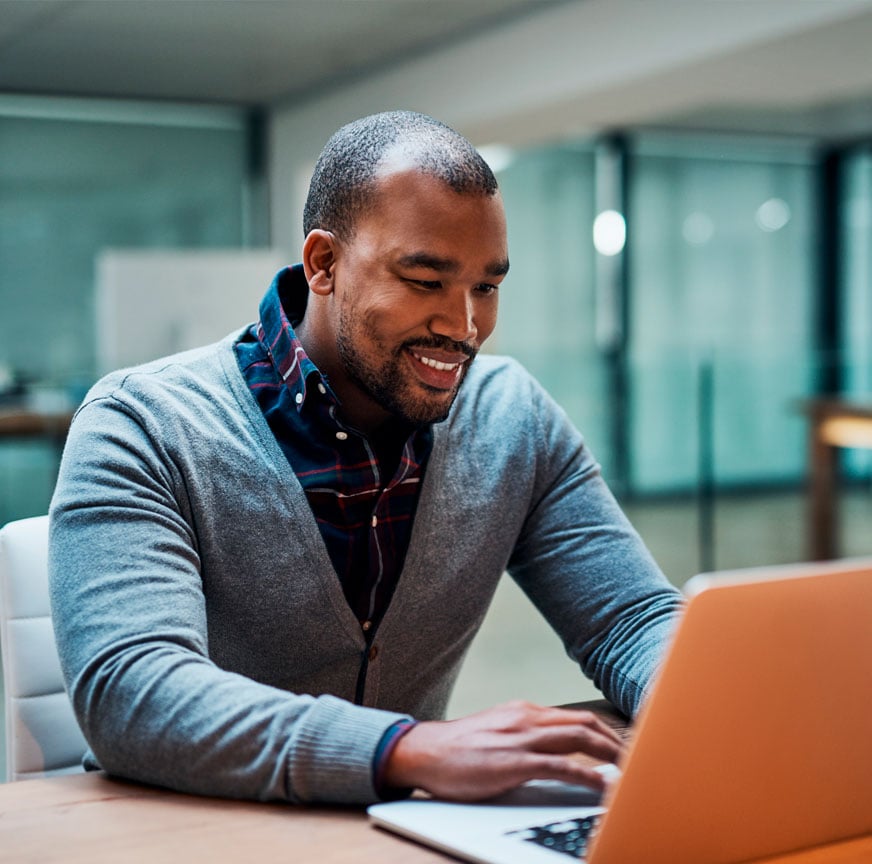 Young man smiling while working on his laptop